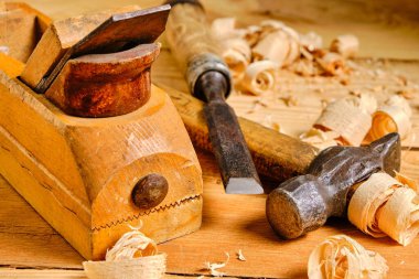 Marangoz alet çantası, çekiç, keski ve uçak ahşap bir arka planda talaş ile