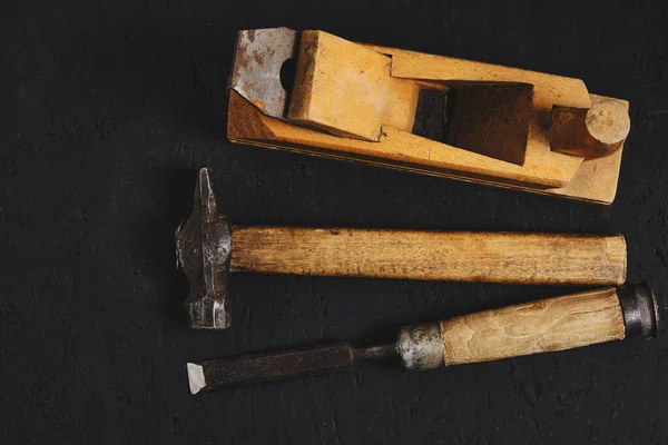 Koyu arkaplanda marangozlar, çekiç, keski ve uçak seti