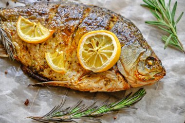 Parşömen kağıdında pişmiş, baharatlı fırında balık, limon ve biberiye.