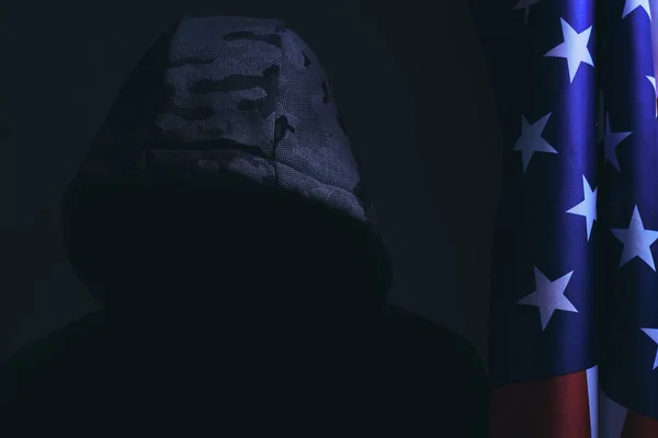 Man Dark Background Hood Hidden Face Dark Stands Next Flag — Fotografia de Stock