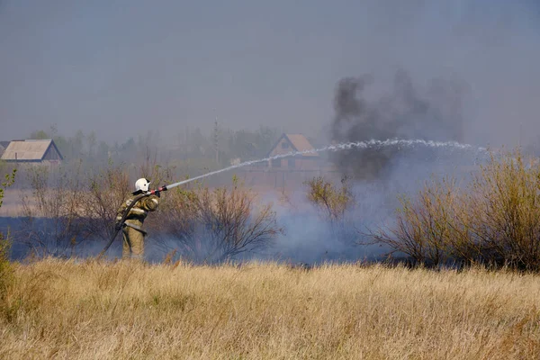 消防员用消防软管扑灭燃烧的干草 — 图库照片