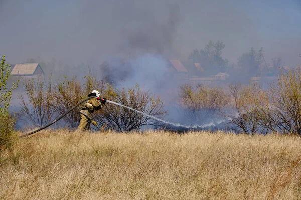 消防员用消防软管扑灭燃烧的干草 — 图库照片