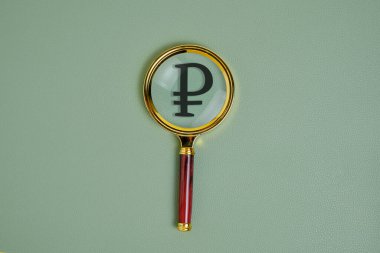 Yeşil arkaplanda büyüteç altında ruble sembolü