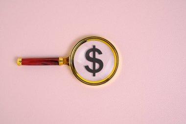Büyüteç altında pembe yeşil arka planda dolar sembolü.