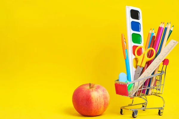 ショッピングカートのアップル 文房具や学校用品 黄色の背景 — ストック写真