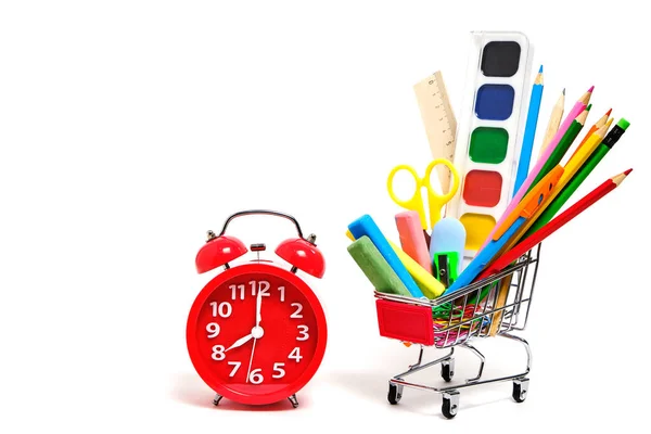 ショッピングカートフルスクール用品やオフィス用品と赤目覚まし時計白の背景 — ストック写真