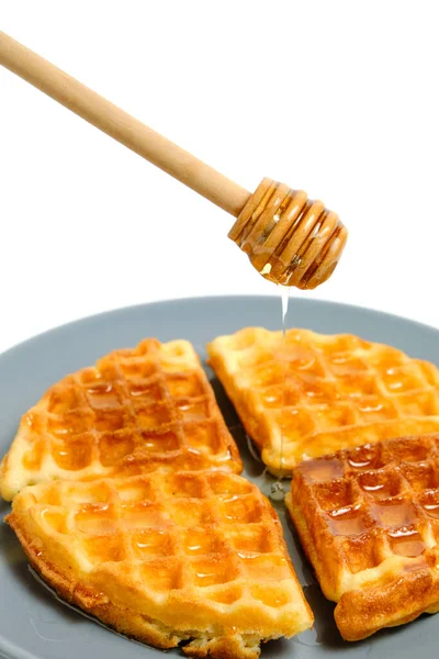 用蜂蜜勺把松软松饼和新鲜蜂蜜倒入盘中 放在白底上 — 图库照片