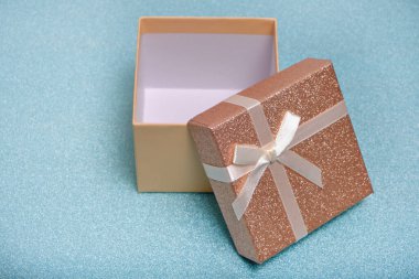 Open gift box with beige ribbon and bow on shiny background