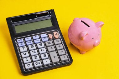 Calculator and piggy bank yellow background.Concept family budget and business