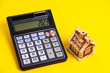 Calculator and house on a yellow background, concept mortgage buying and selling housing