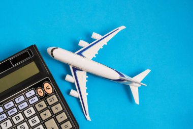 Airplane model and calculator blue background.Concept of costs or expenses for air travel.Budget of trip