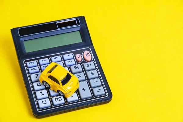 Toy car and calculator yellow background.Concept buying car