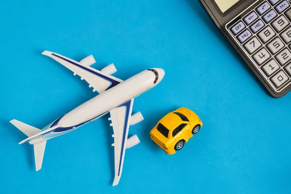 Calculator,model an airplane and car blue background. Concept costs expenses for air travel and transportation costs