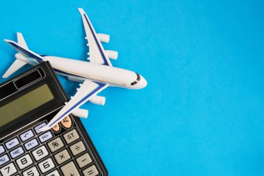 Airplane model and calculator blue background.Concept of costs or expenses for air travel.Budget of trip
