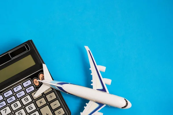 Airplane model and calculator blue background.Concept of costs or expenses for air travel.Budget of trip