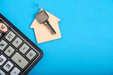 Calculator and keychain with house keys blue background.Concept mortgages, buying and renting housing