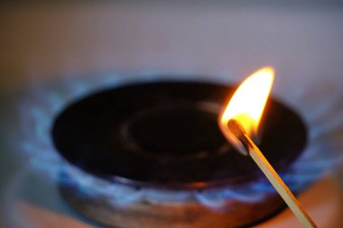 Burning match against background blue flame burning burner