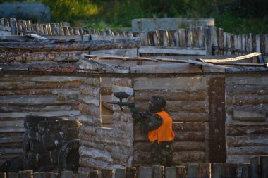 Team paintball player hides behind shelter equipped and armed