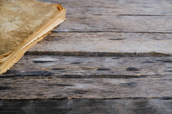 Old battered and yellowed book on wooden background