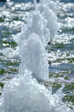 Foam jets of water and shine of sunlight from the fountain bright sunny day