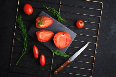 Dilimlenmiş domatesler, ızgarada ahşap saplı dereotu ve bıçağı.