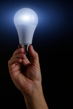 LED çevre dostu ampul elinde siyah arkaplanda