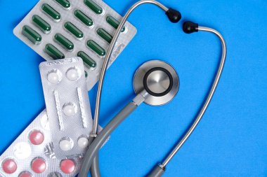 Stetoskop ve haplar mavi arka plan. Kalp hastalıkları ve tedavi kavramları