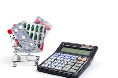 Alışveriş arabası, hesap makinesi ve haplar beyaz arka plan