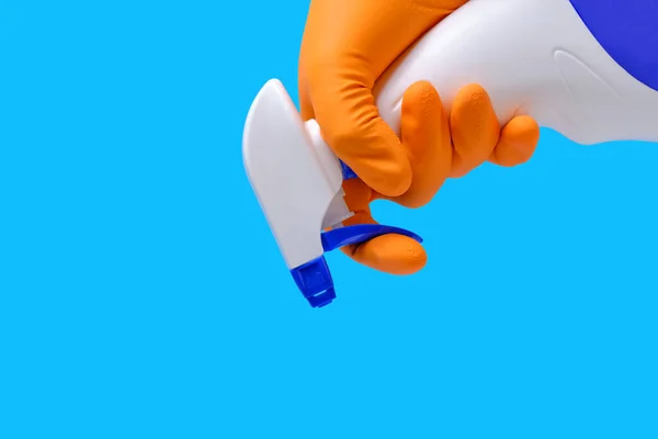 Sprayer for cleaning windows and plumbing in hand with glove on blue background