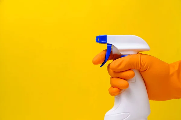 Sprayer for cleaning windows and plumbing in hand with glove on yellow background