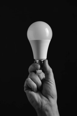 LED çevre dostu lamba elinde siyah arka planda