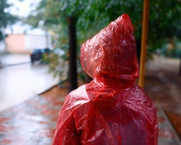 Женщина под дождем в плаще на автобусной остановке — стоковое фото