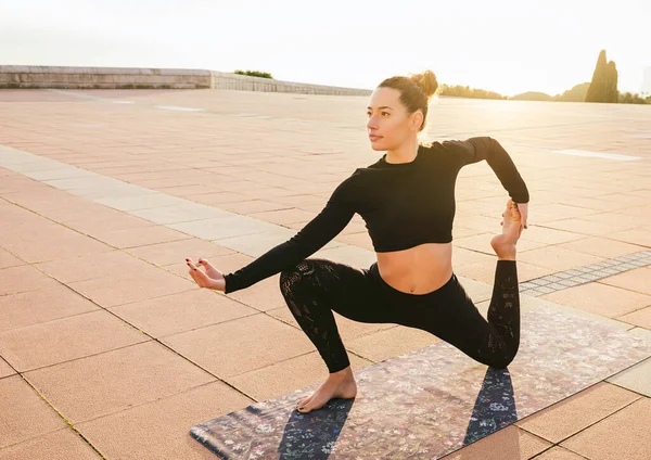 Young woman doing a yoga posture. Sunset light