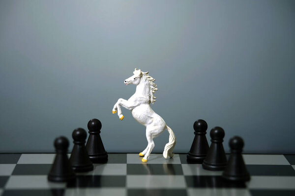 Miniature of white prancing horse standing on chessboard in the middle of pawn line isolated on grey background. Image photo