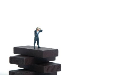 Dürbün kullanan bir işadamı tahta engelli merdivenlerin üzerinde duruyor. Minyatür minyatür insanlar fotoğraf çekmeyi sever. beyaz arkaplanda izole.