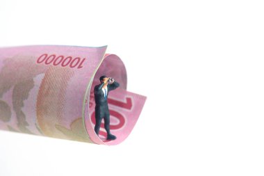 Dürbün kullanan bir iş adamı rulo para kağıdının içinde duruyor. Minyatür minyatür insanlar fotoğraf çekmeyi sever. beyaz arkaplanda izole