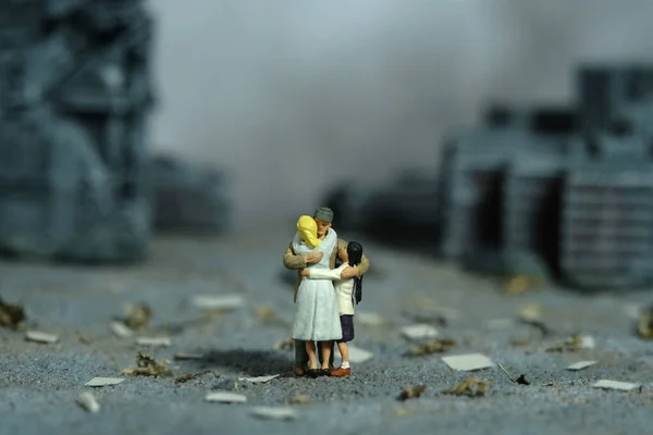 Miniature people toy figure photography. Family reunion concept. Father hugging his wife and daughter in the middle of ruined demolish city. Image photo