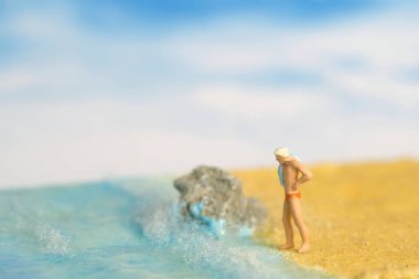 Minyatür insanlar oyuncak fotoğrafçılık. Deniz kıyısında yüzemeyeceğinden emin olmayan bir adam. Resim fotoğrafı.