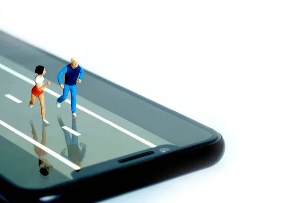 Running and jogging tracking app concept. A men and women running above smartphone. Miniature people figure photography.