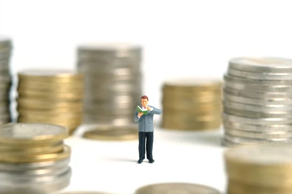 Miniature people toy figure photography. A men student standing in the middle of money coin stack, isolated on white background. Image photo