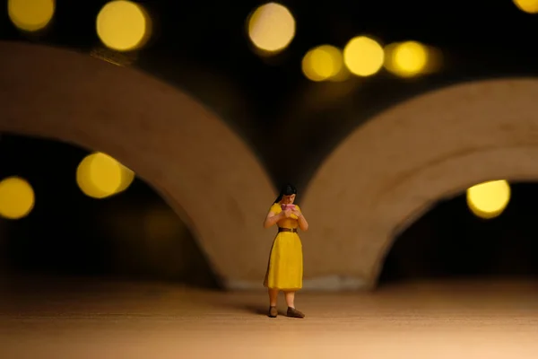 Miniature people toy figure photography. A girl reading a book at night with bokeh defocused light lamp, bed time routine before sleep. Image photo
