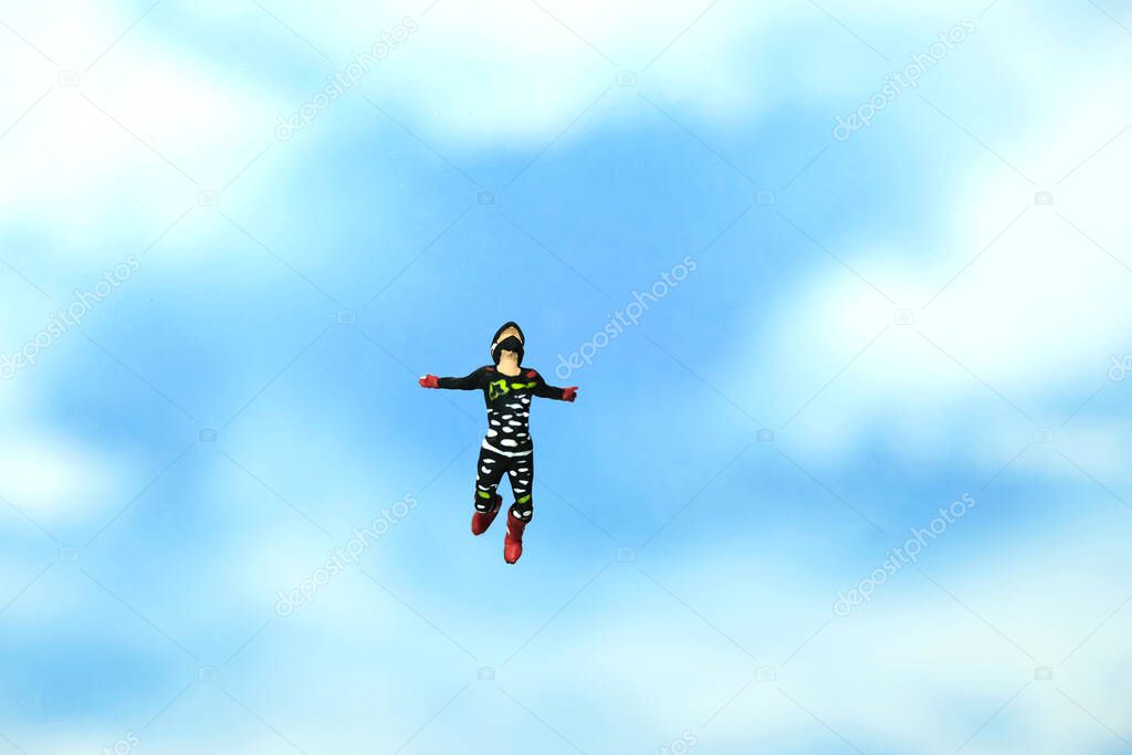Miniature people toy figure photography. A men doing sky diving jump in cloudy bright day. Image photo