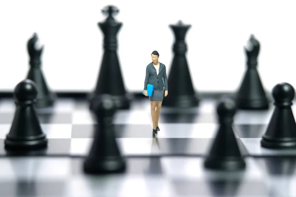 Miniature people toy figure photography. A businesswoman walking above chessboard in the middle of chess piece. Isolated on white background. Image photo