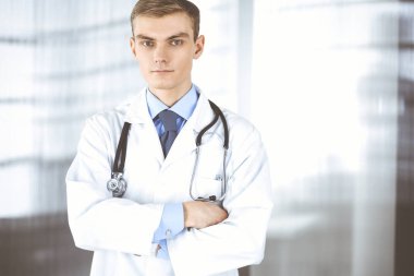 Steteskoplu bir doktor hastane ofisinde duruyor. Klinikte mükemmel bir tıbbi hizmet. Tıp ve sağlık sektöründe mutlu bir gelecek