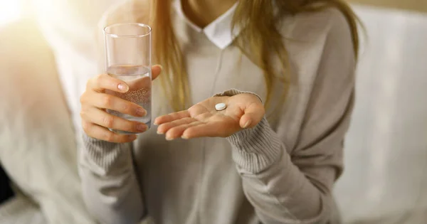 Close-up woman holding pills time to take medications, cure for headache. Medicine concept during self isolation and Coronavirus pandemic