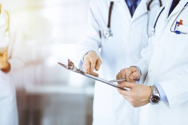 Doktorlar, iki erkek ve bir kadın, güneşli hastane ofisinde dikilen tıbbi muayene sonuçlarını tartışırlar. Doktorlar ilaç kayıtlarını doldurmak için pano kullanıyorlar. Klinikte mükemmel bir sağlık hizmeti