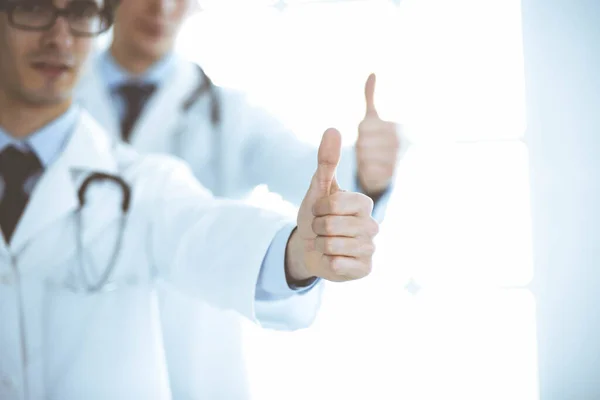 Twee mannelijke artsen staan als een team en tonen duimen omhoog als een symbool van de beste service voor patiënten in de kliniek. Geneeskunde en gezondheidszorg — Stockfoto