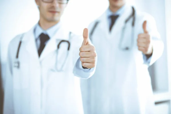 Twee mannelijke artsen staan als een team en tonen duimen omhoog als een symbool van de beste service voor patiënten in de kliniek. Geneeskunde en gezondheidszorg — Stockfoto