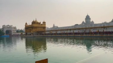 Amritsar 'daki altın tapınak, önünde su ve kalabalık tapınağın içinde namaz kılmak için girişte bekliyor..