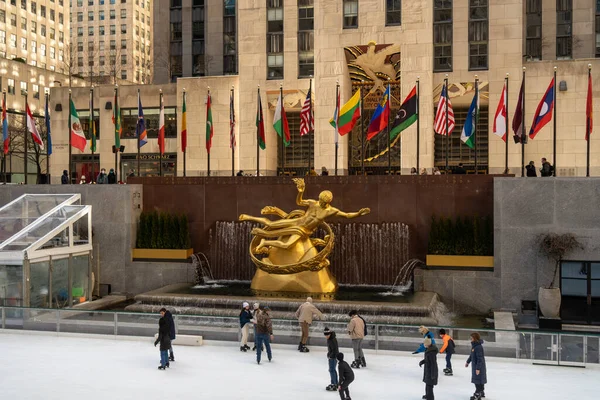 New York City, New York; 19 Şubat 2022: New York 'taki Rockefeller Center' da buz pateni ve Manhattan siluetinin keyfini çıkaran yerli ve turistler.